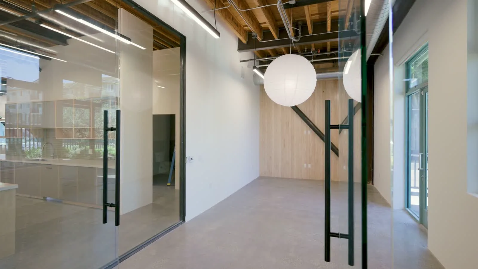 Ground-floor creative space at 1447 Cloverfield — glass-walled offices and exposed wood ceilings